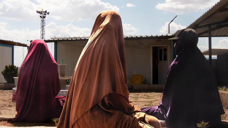 Deux enfants et une femme voilées photographiées de dos.