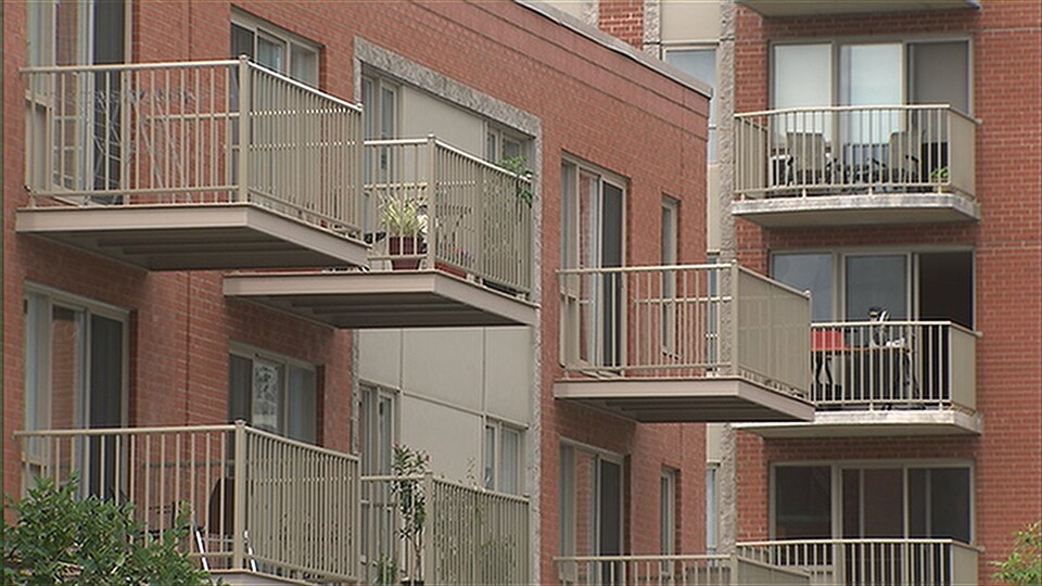 Vue sur des balcons d'un immeuble à condos avec des plantes et des chaises.
