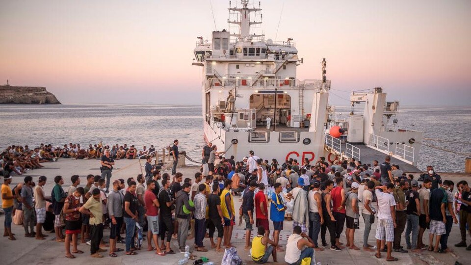 Des migrants font la file pour embarquer sur un bateau.