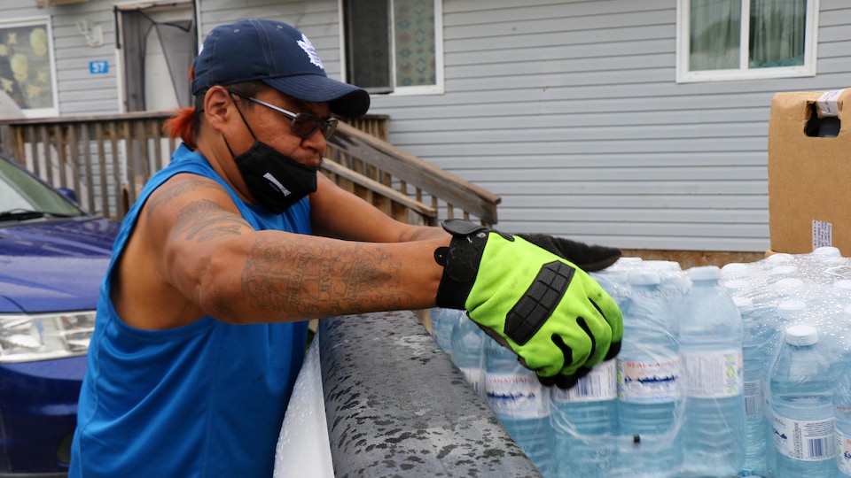 Un homme prend une caisse de bouteilles d'eau de son camion.