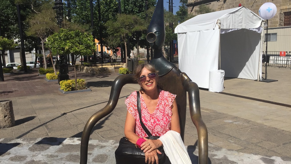Une femme est assise sur une statue dans un parc