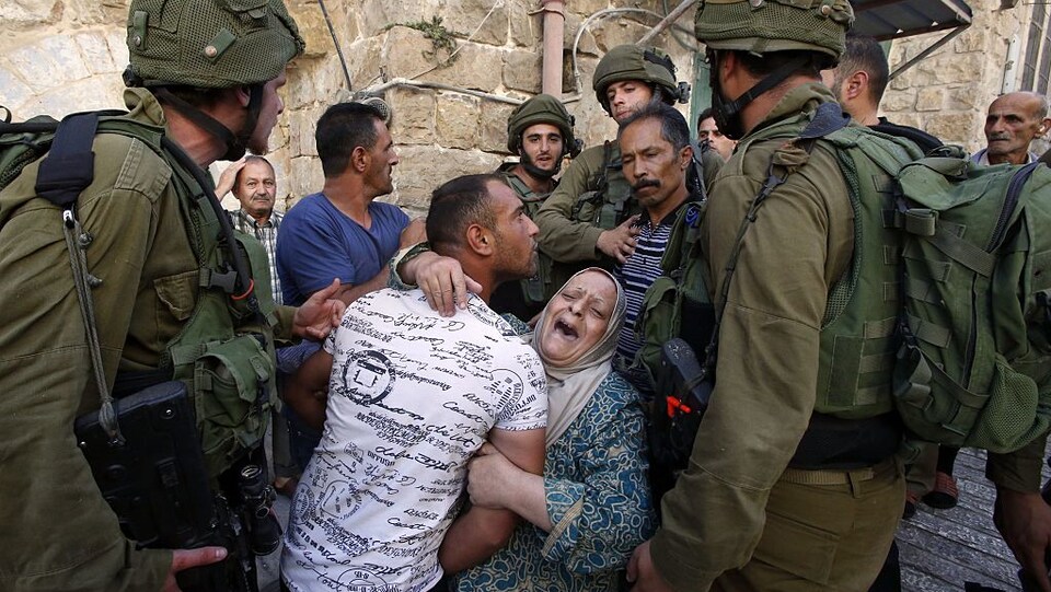 Une femme palestinienne essaie d'empêcher l'arrestation d'un Palestinien par des soldats israéliens dans la ville d'Hébron, en Cisjordanie, occupée par Israël.