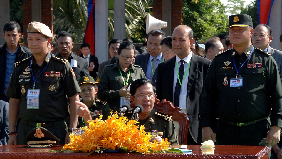 Le Premier ministre cambodgien, Hun Sen est assis à une table et est entouré de gradés et de membres de son gouvernement.