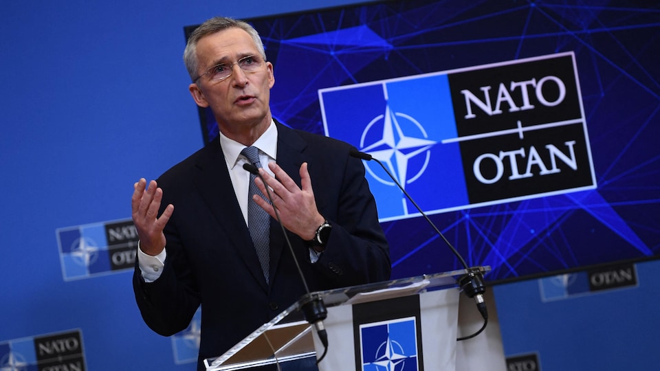 Jens Stoltenberg parle à la presse devant une affiche avec le logo de l'OTAN.