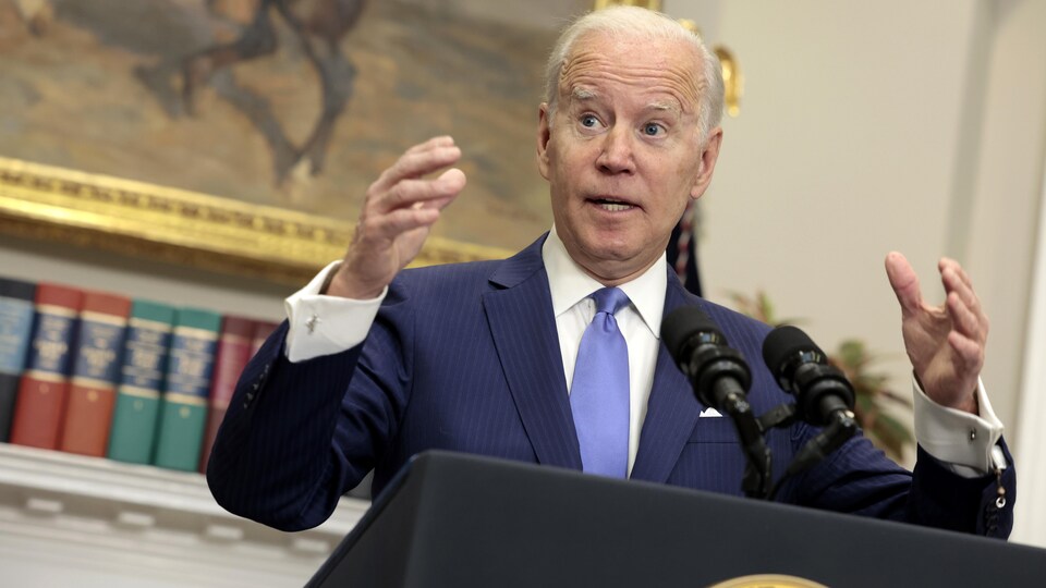 Joe Biden, les bras écartés, devant un lutrin. 