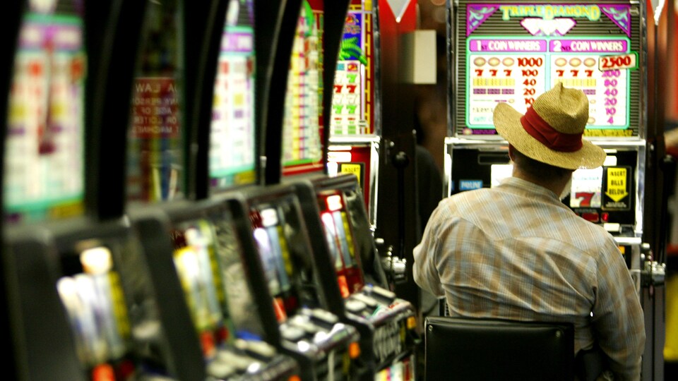 Un homme assis devant une machine à sous dans un casino.