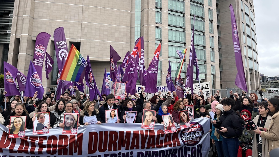 Des personnes manifestent devant un immeuble en tenant des photos de femmes victimes de féminicides en Turquie.