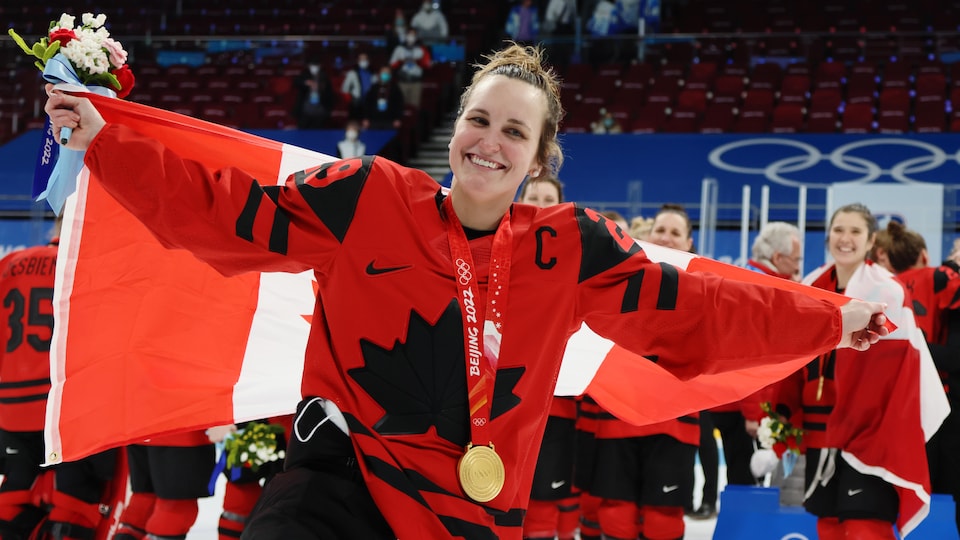 La hockeyeuse, médaille d'or au cou, fête avec ses coéquipières d'Équipe Canada après la finale aux Jeux olympiques d'hiver à Pékin. 