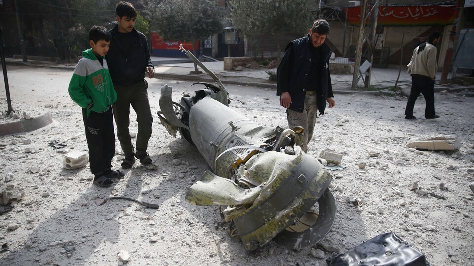 Des personnes examinent les restes d’un des nombreux missiles reçus sur la ville de Douma près de Damas en Syrie.