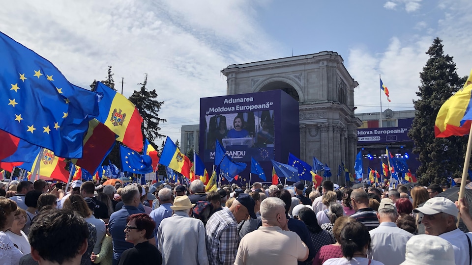 Des milliers  de personnes tenant des drapeaux de l'Europe devant un écran où il est écrit Europe pour a Moldavie.