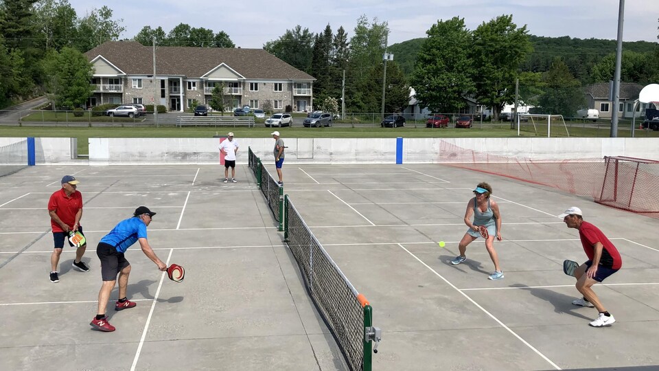 Quatre joueurs de pickleball en pleine partie.