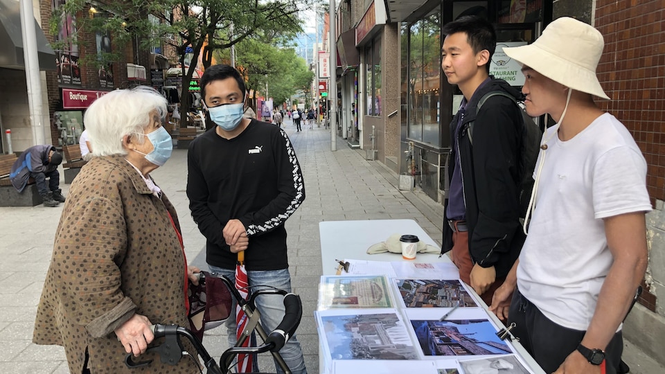 Une femme âgée d'origine chinoise discute avec des jeunes hommes dans une des rues du quartier chinois de Montréal.