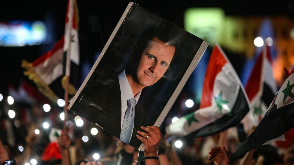Des Syriens célèbrent dans les rues de Damas, la capitale de la Syrie, en brandissant drapeaux syriens et affiche à l'effigie de Bachar al-Assad.