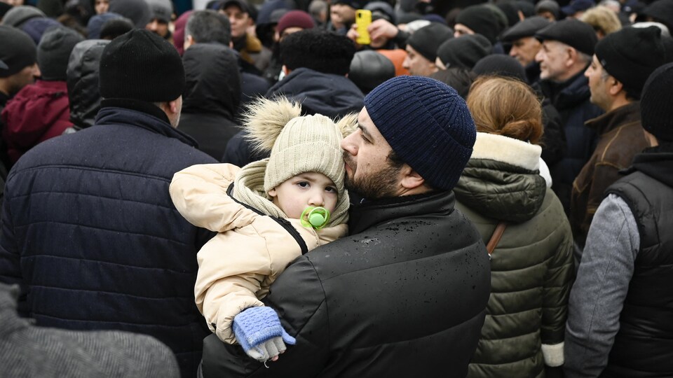 Un homme tient son enfant dans ses bras alors que des familles ukrainiennes attendent d'entrer dans un camp de réfugiés à Chisinau, en Moldavie. 
