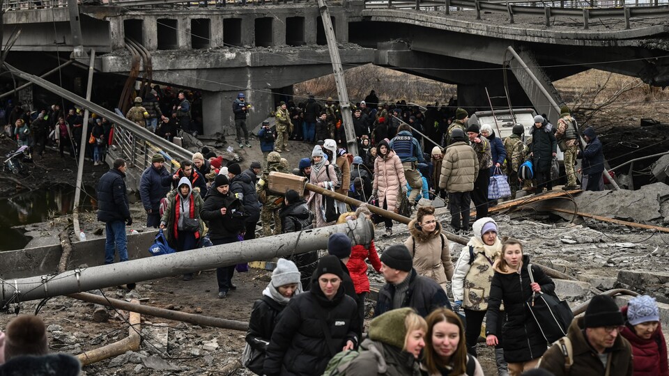 Des personnes marchent sur les débris d'un pont détruit par une explosion.