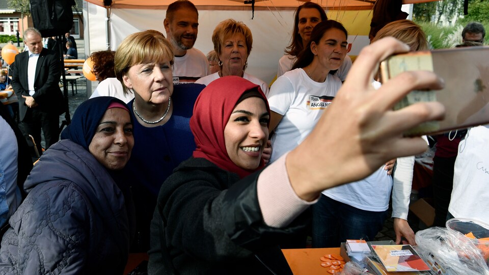 Une réfugiée syrienne (D) et sa mère (G) posent pour une autophoto avec la chancelière allemande Angela Merkel (C), à une semaine des élections allemandes.