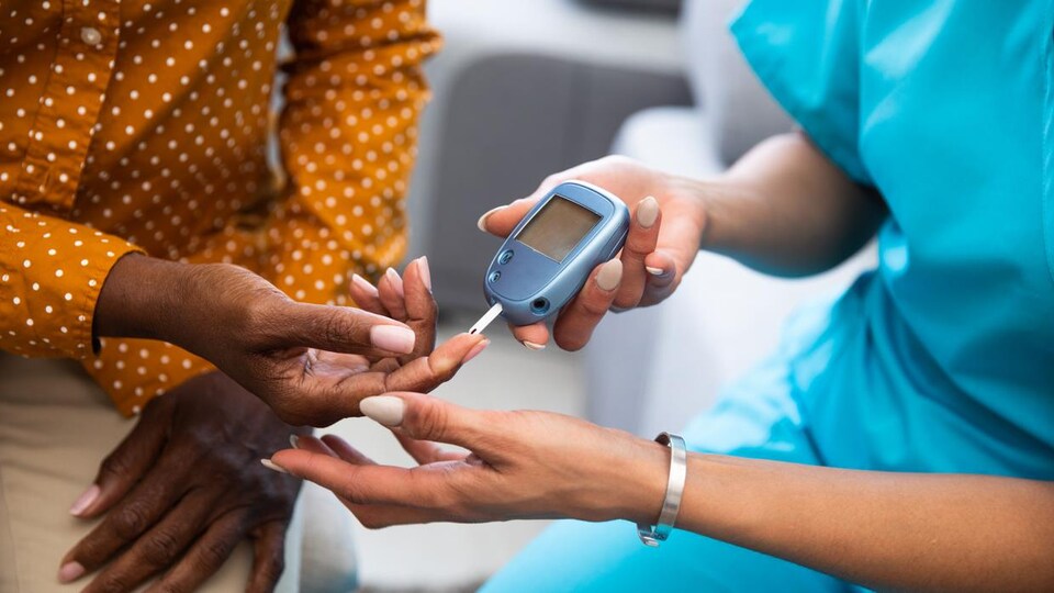 Une infirmière fait un test de glucose a un patient.