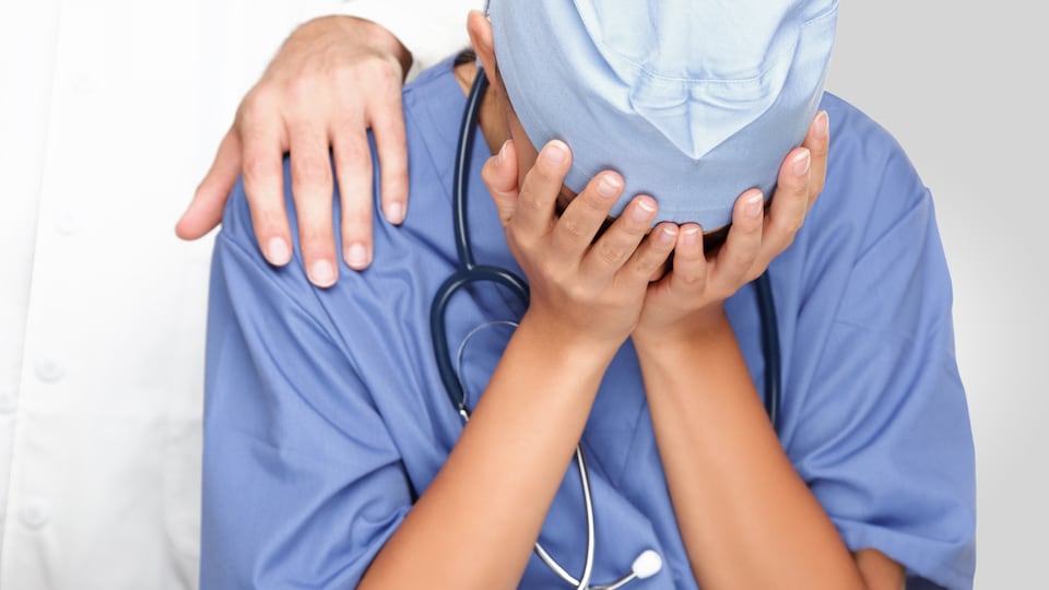 Un médecin, le visage caché par ses mains, semble épuisé.