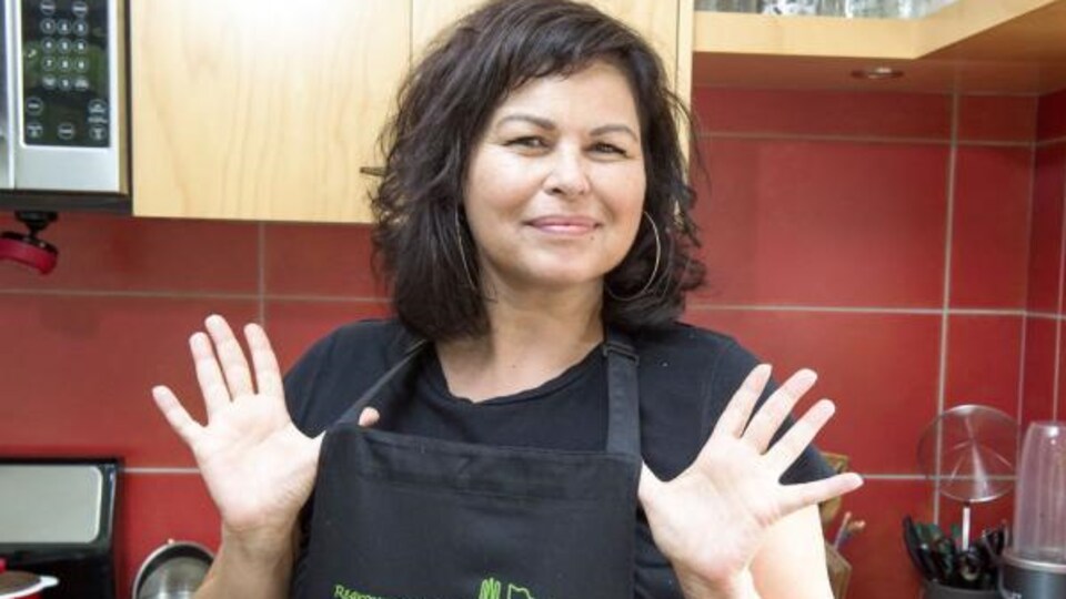 Dominique Pétin, porte-parole du Regroupement des popotes roulantes, portant un tablier, dans une cuisine