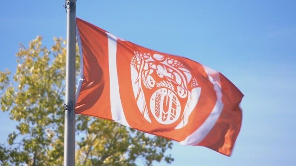 Un drapeau de vérité et réconciliation hissé. Le drapeau est orange avec des éléments qui ont été choisis par les survivants.

