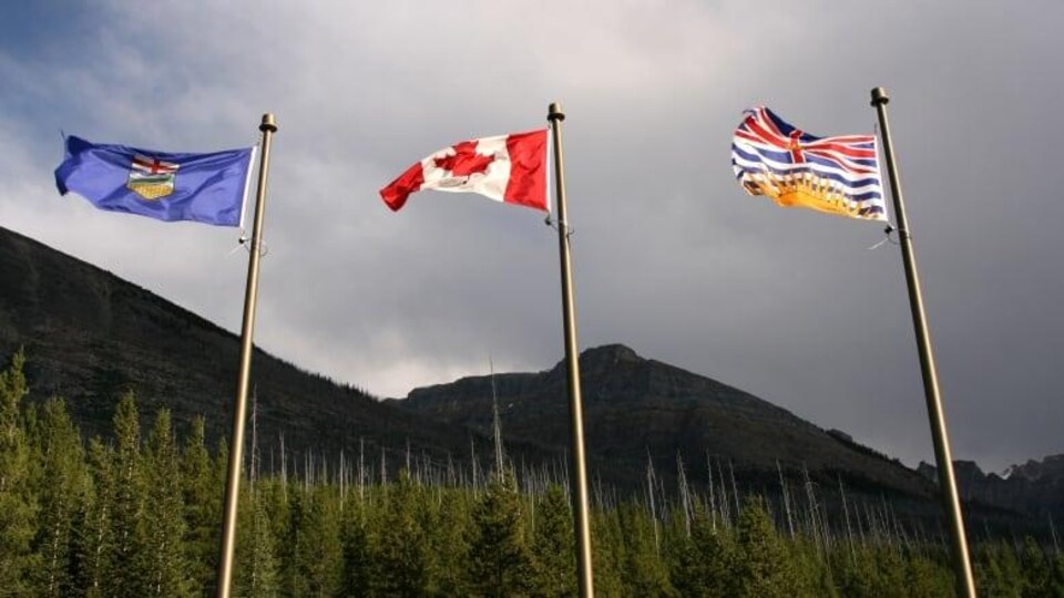 Trois drapeaux côte-à-côte dans le vent, un de l'Alberta, un du Canada et un de la Colombie-Britannique.