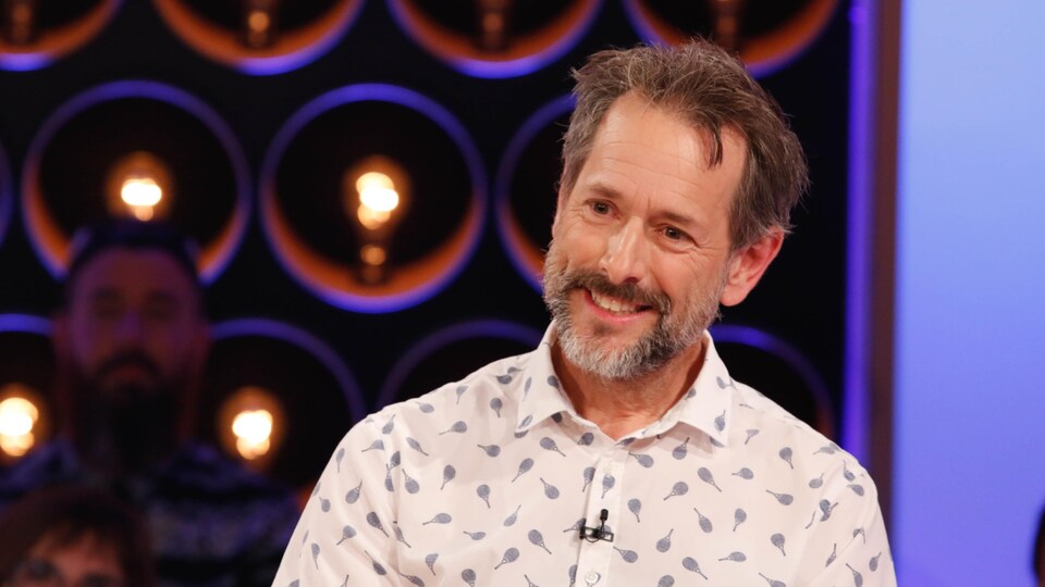 Marc-André est souriant, il porte la barbe et une chemise à motif de raquettes