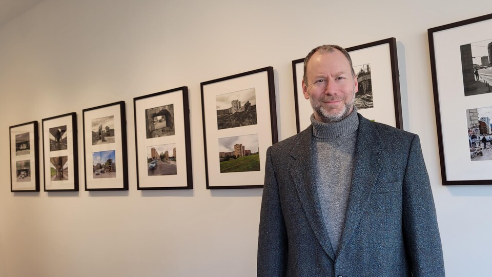 Un homme devant une série de photographies encadrées