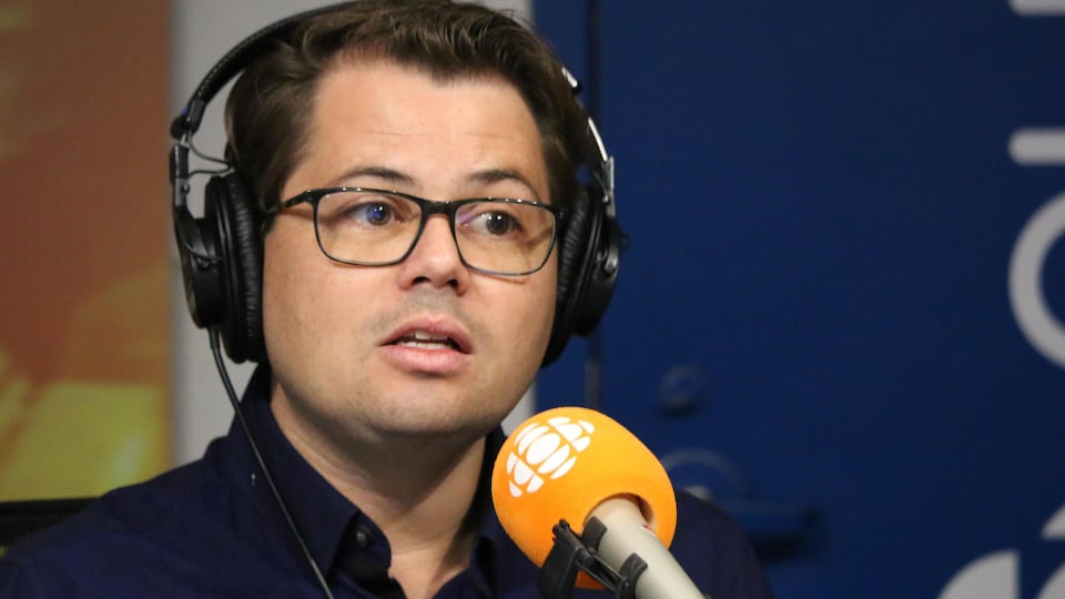 Un homme derrière un micro dans un studio de radio