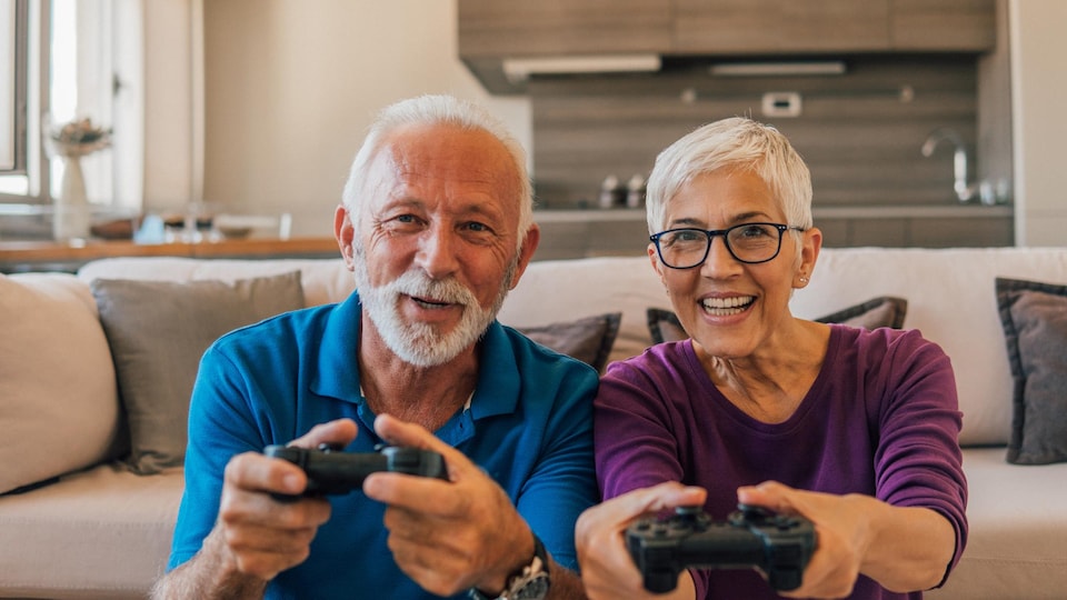 Une couple d'aînés joue à un jeu vidéo.