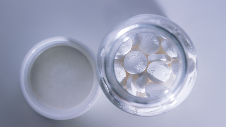 Un contenant en verre rempli d'aspirine