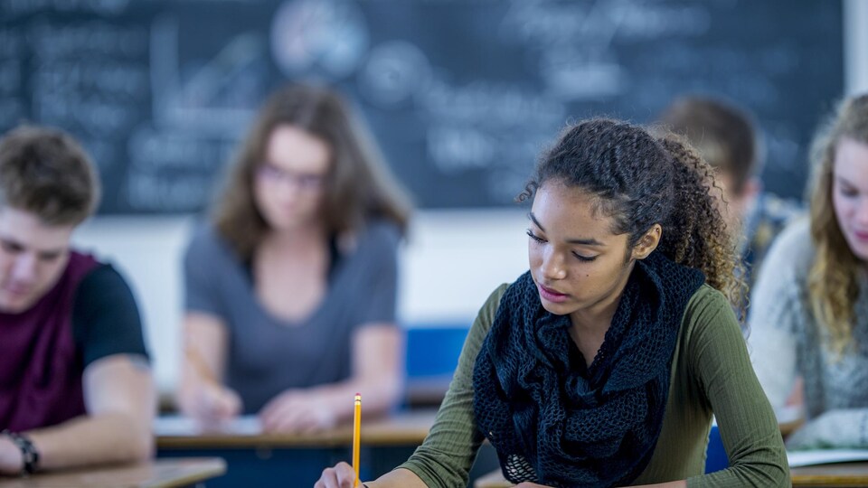 Une étudiante passe un examen en classe.