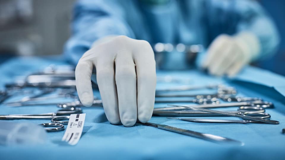 Un chirurgien prend un instrument dans sa main.