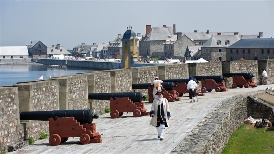 Un soldat se promène près des canons sur les murs de la Forteresse de Louisbourg.