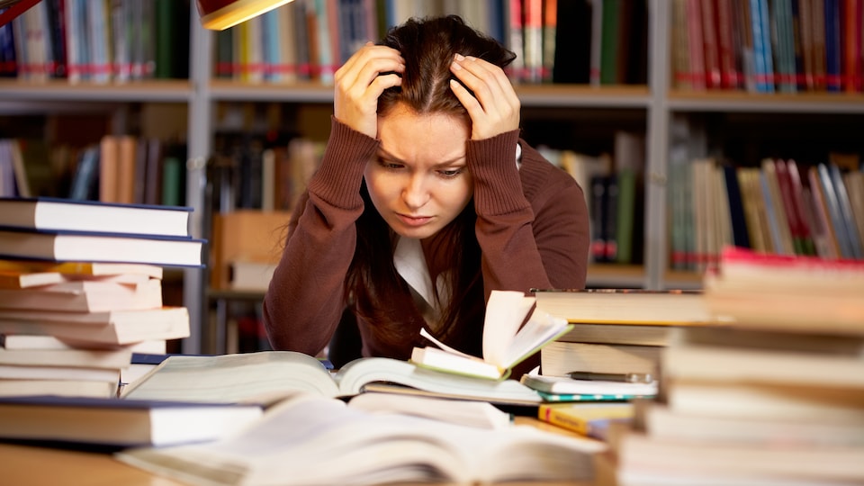 Une étudiante découragée devant ses livres.