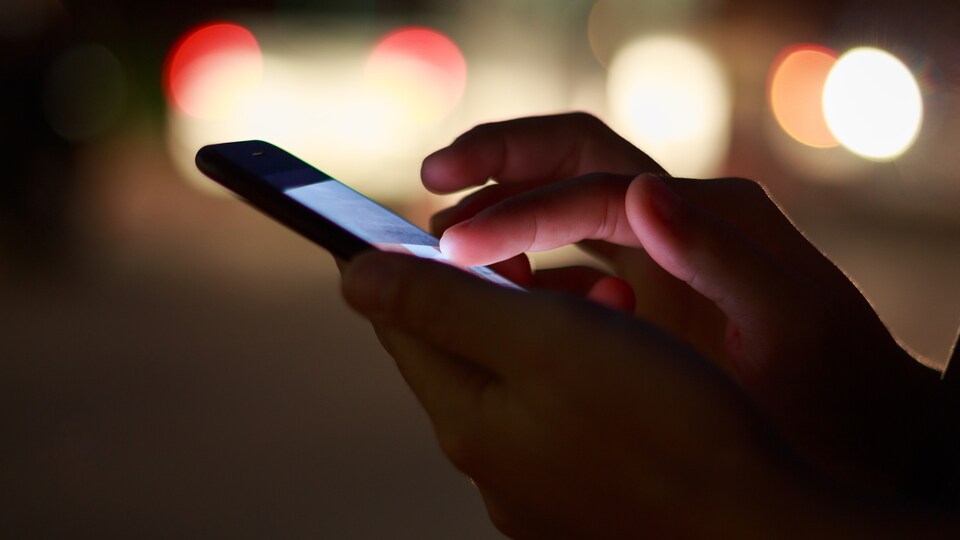 Un homme consulte son téléphone cellulaire.
