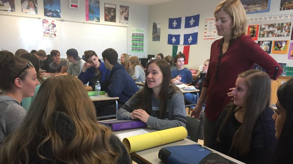 Des jeunes adolescents sont assis dans leur salle de classe et discutent en compagnie de leur enseignante de français.