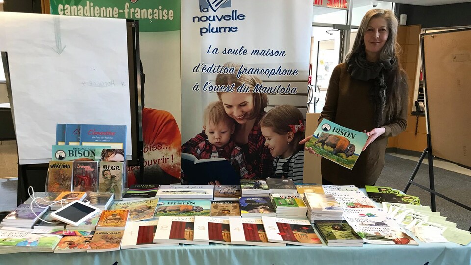 Une femme présente un livre à un kiosque de la maison d'édition.