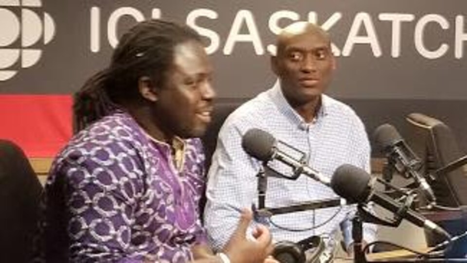 Deux hommes discutent au micro des studios de radio de Radio-Canada à Regina.