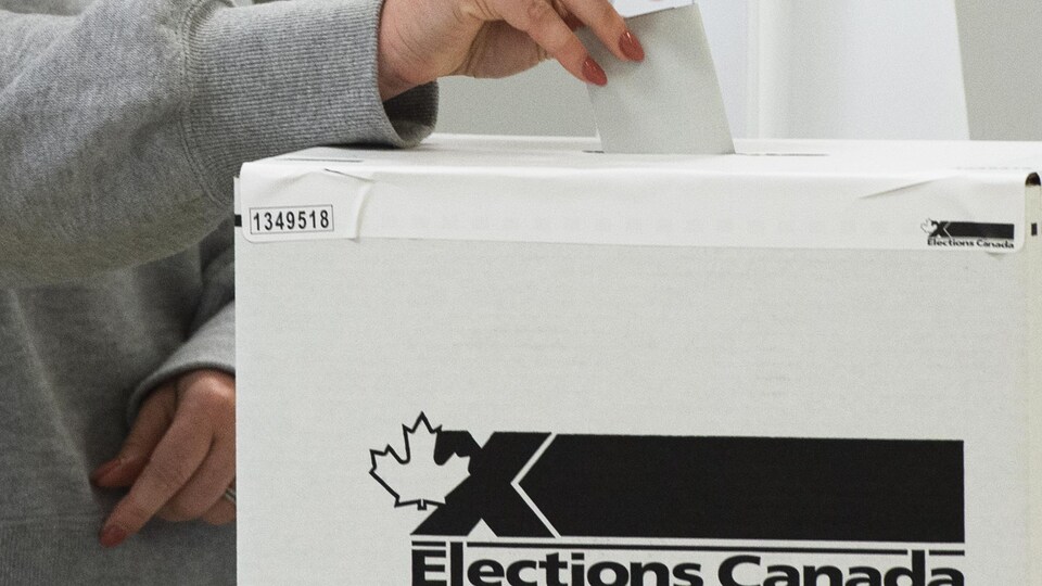Une électrice insère son bulletin de vote dans l'urne.