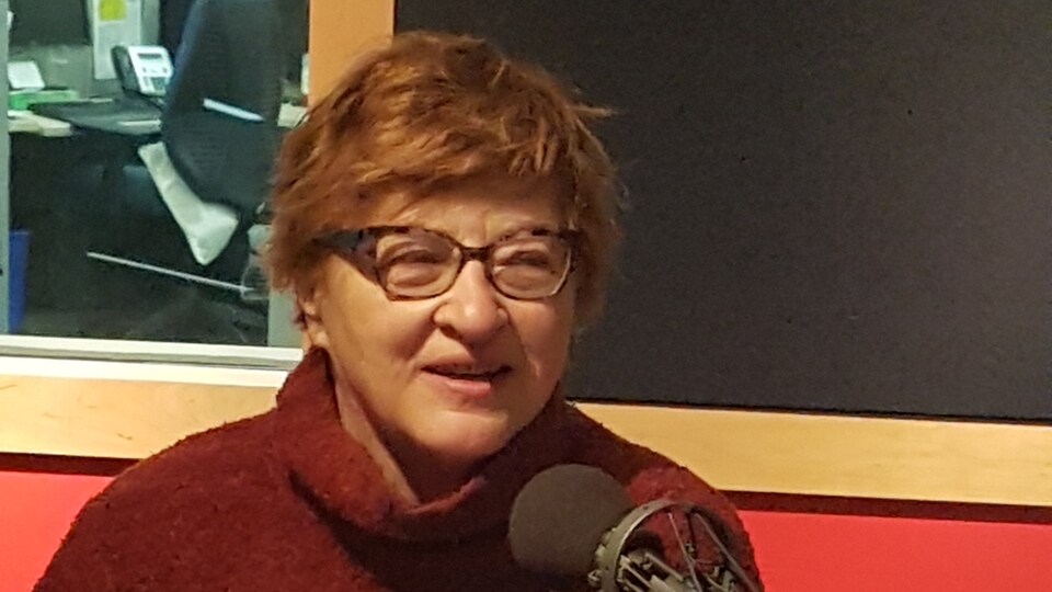 Une femme est assise devant un micro dans un studio de radio.