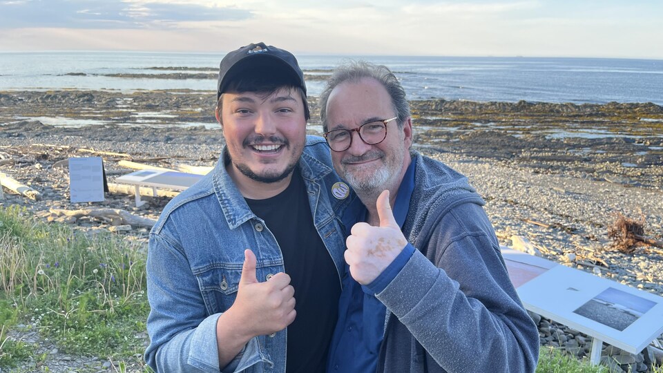 Deux hommes souriant prennent la pause le pouce en l'air, sur le bord du Saint-Laurent à Petite-Vallée.
