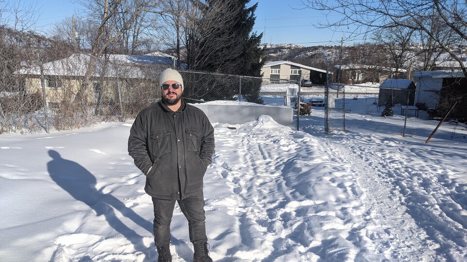L'artiste Emilio Portal, vêtu d'un manteau en jeans, debout devant un paysage d'hiver.