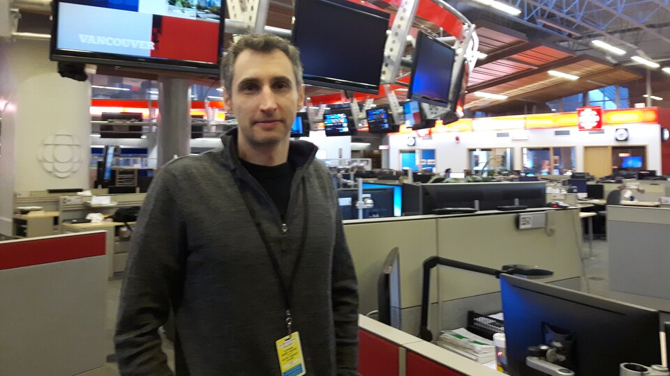 Un homme pose debout dans une salle de nouvelles.