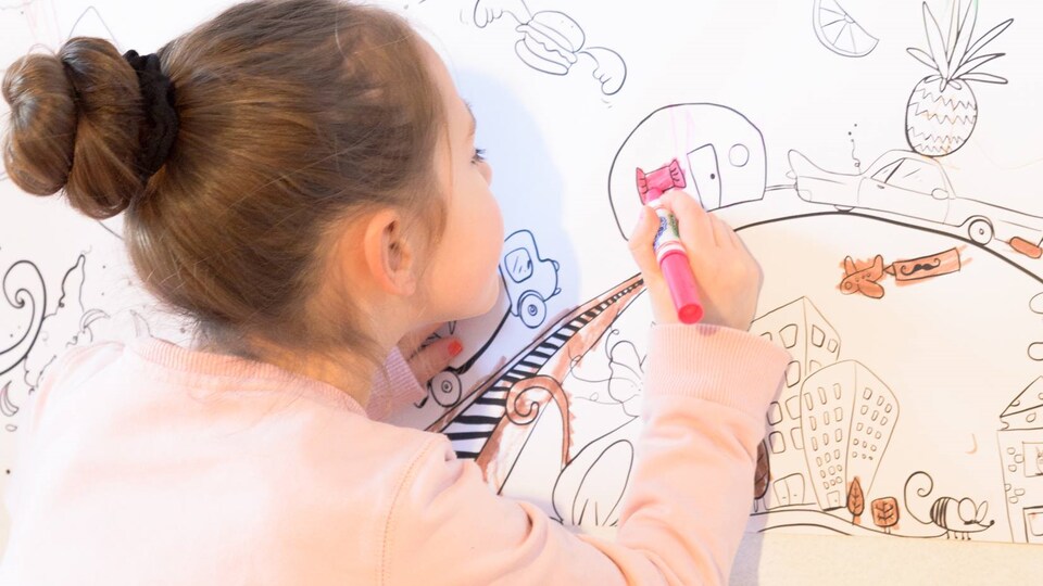 Petite fille qui dessine sur un tableau