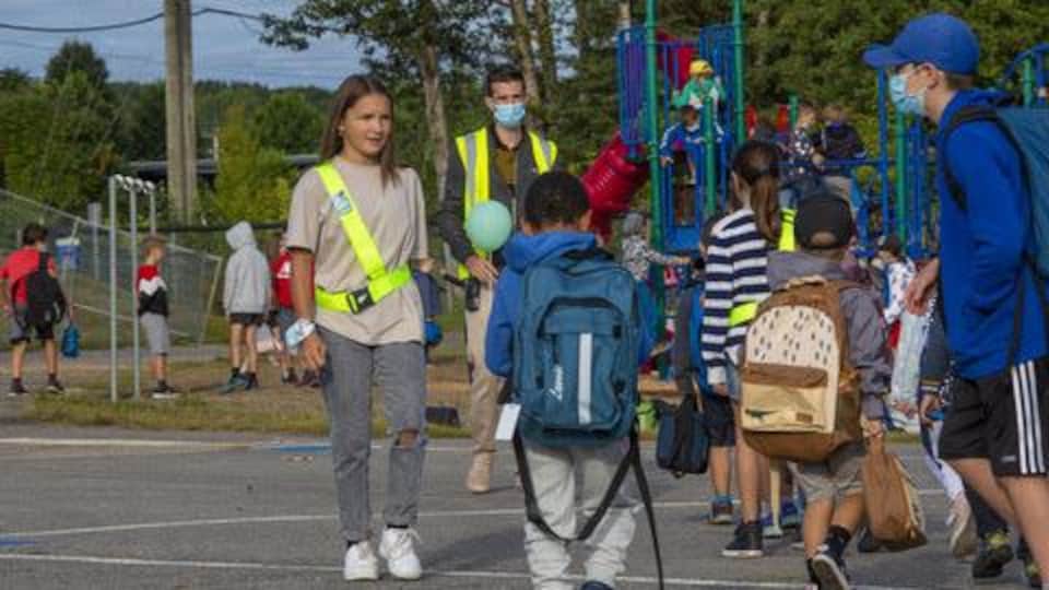 Des brigadiers parlent avec des enfants dans une cour d'école.