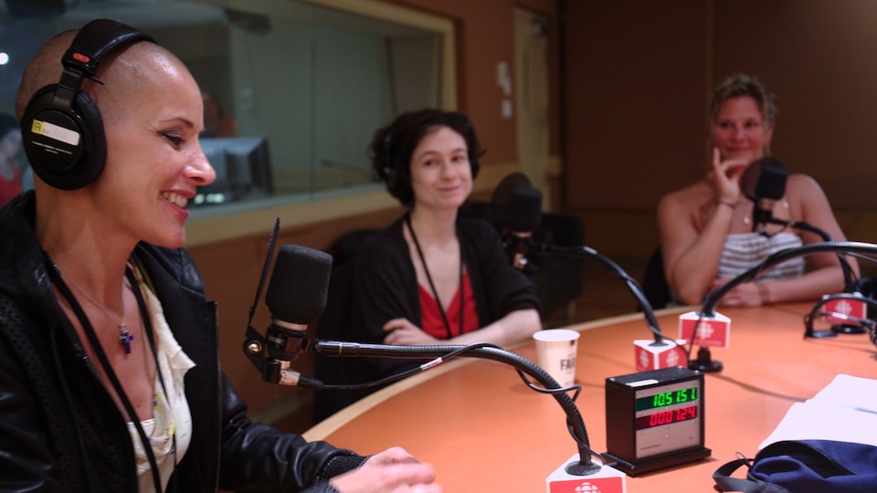Les trois sont assise à une table ronde sur laquelle se trouvent des micros.