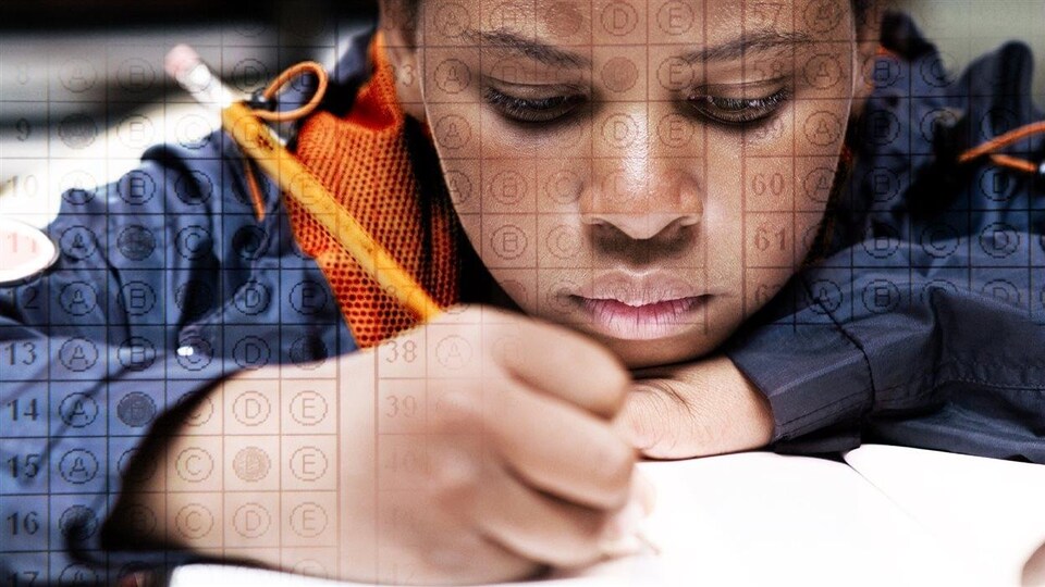 Un jeune, crayon à la main, remplit les pages d'une test scolaire.