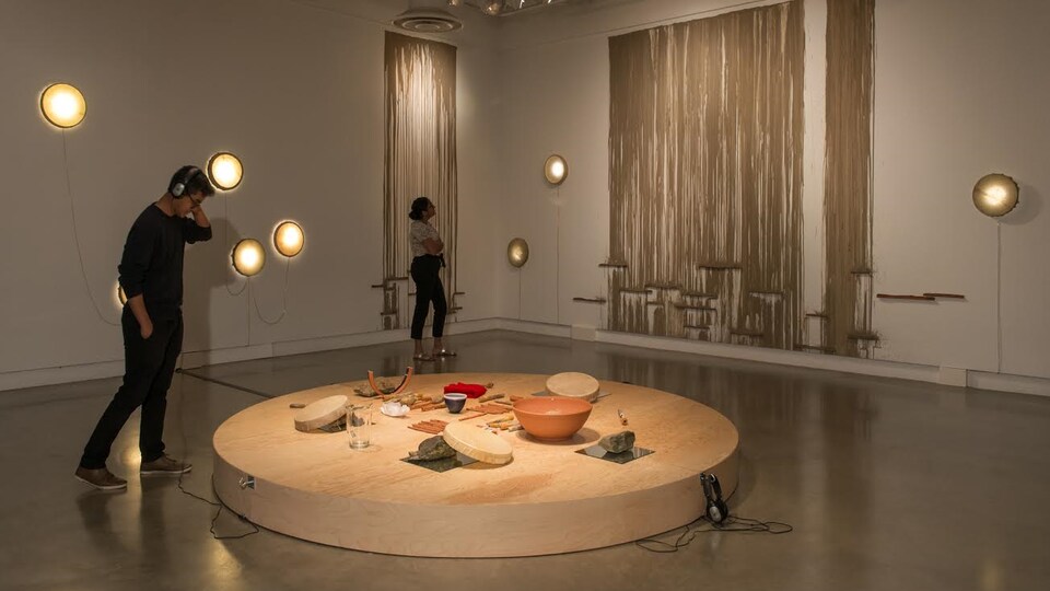 Salle d'exposition avec une oeuvre au centre de la pièce et quelques-une au mûré