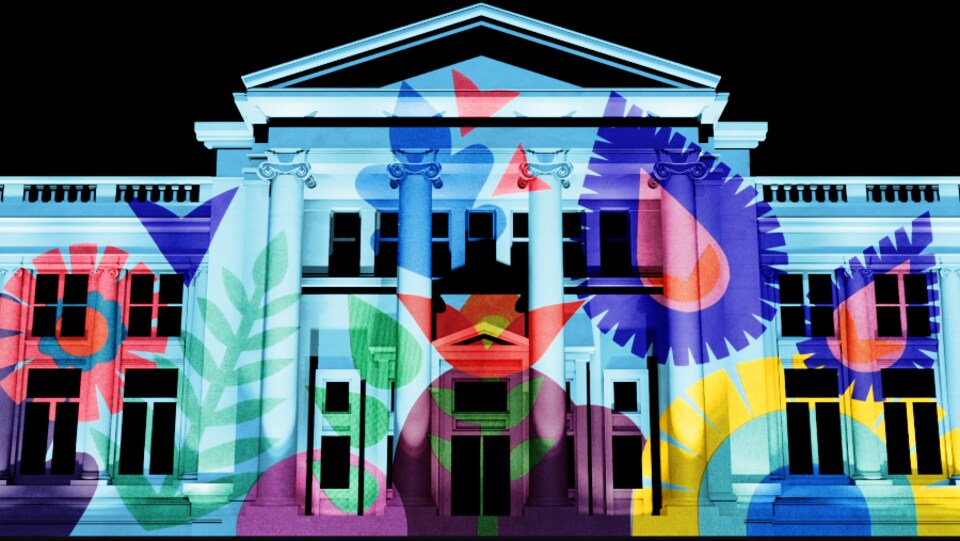 Une oeuvre toute en couleur est projetée sur toute la largeur de la façade du musée, la nuit.