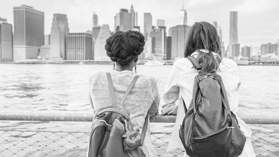 Deux jeunes femmes regardent l'horizon, un sac sur le dos.